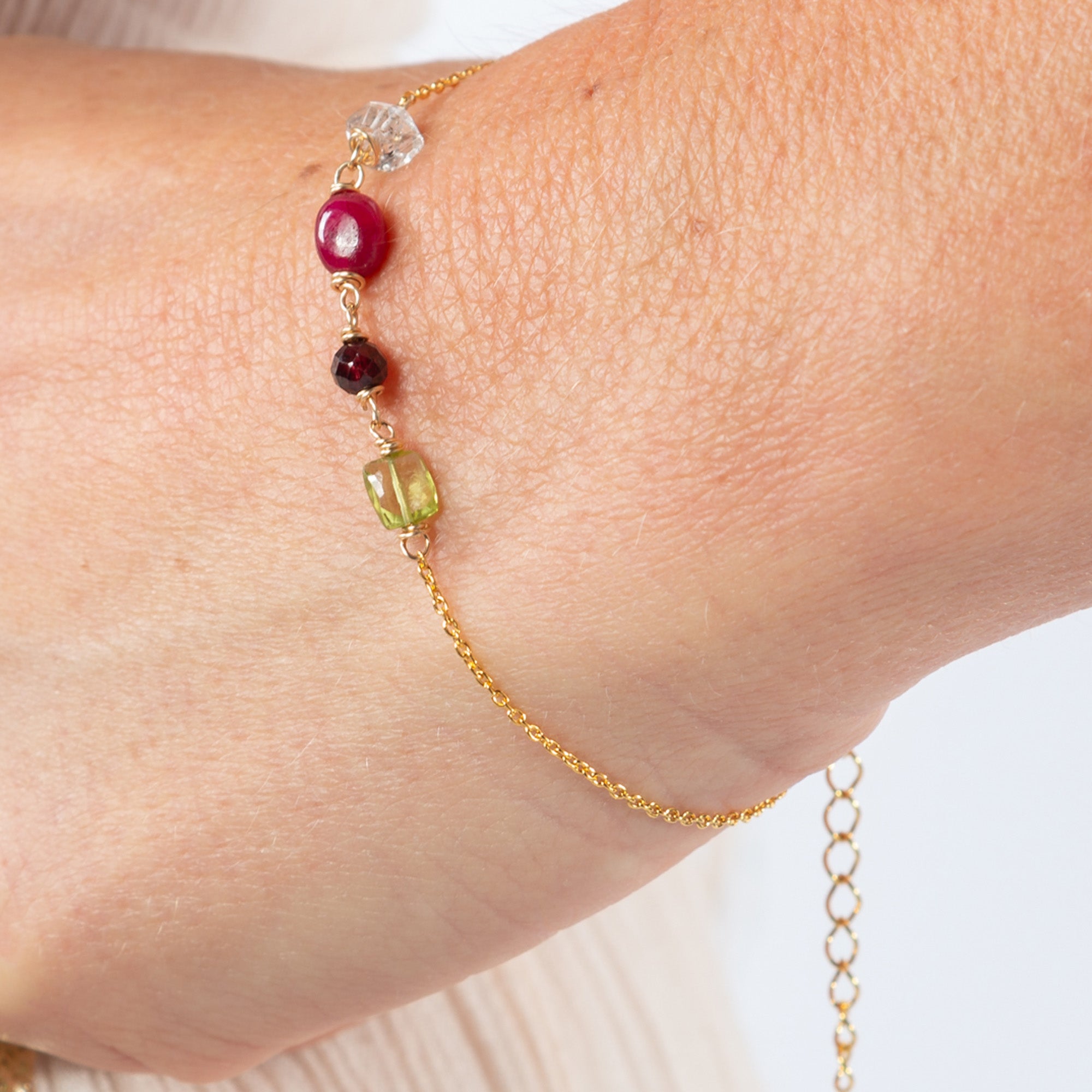 Detail van geboortesteenarmband met natuurlijke edelstenen zoals bergkrisatal, granaat, robijn en peridoot.
