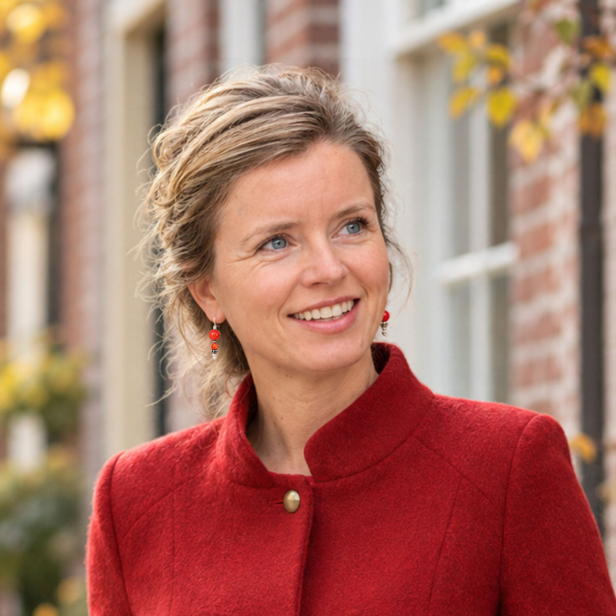 model met rode oorbellen in en jasje in modekleur rood
